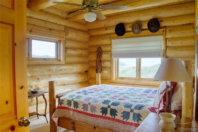 bedroom featuring rustic walls, ceiling fan, and multiple windows