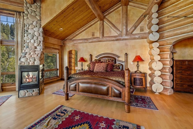 bedroom with hardwood / wood-style floors, a fireplace, high vaulted ceiling, and rustic walls