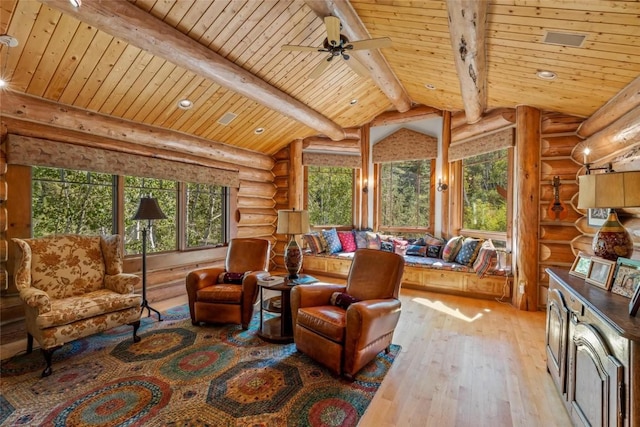 living area with a wealth of natural light, light hardwood / wood-style flooring, and vaulted ceiling with beams