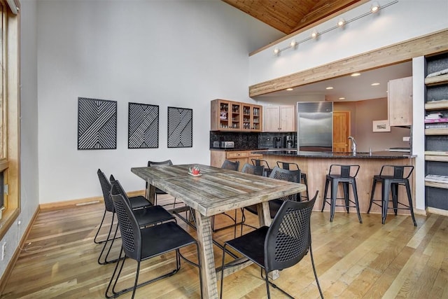 dining space featuring sink, high vaulted ceiling, wood ceiling, and light hardwood / wood-style floors