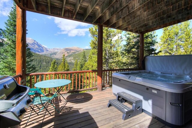 wooden terrace featuring a grill, a mountain view, and a hot tub