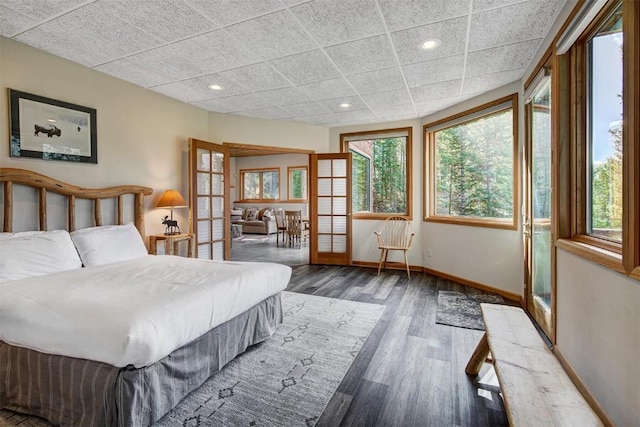 bedroom featuring a drop ceiling, dark hardwood / wood-style flooring, and french doors