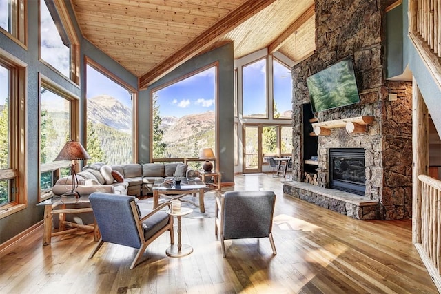 sunroom featuring lofted ceiling, a stone fireplace, wood ceiling, and a wealth of natural light