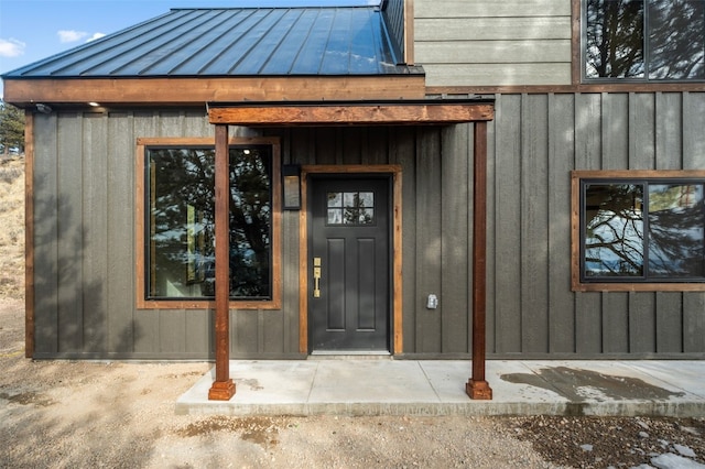 view of exterior entry featuring board and batten siding, a standing seam roof, and metal roof