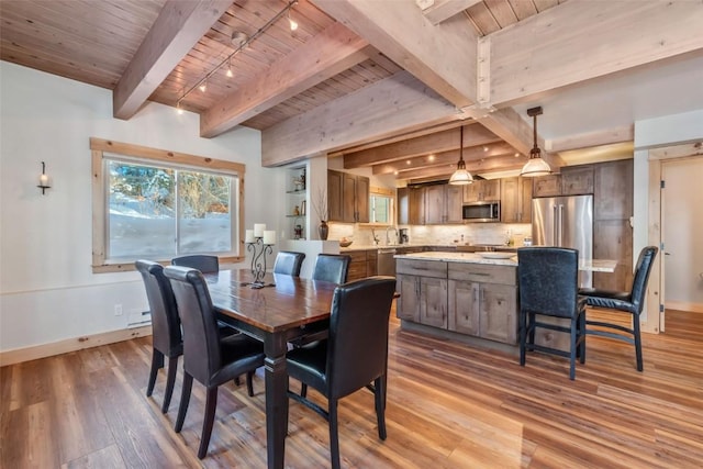 dining area featuring rail lighting, light wood-type flooring, beamed ceiling, and wood ceiling