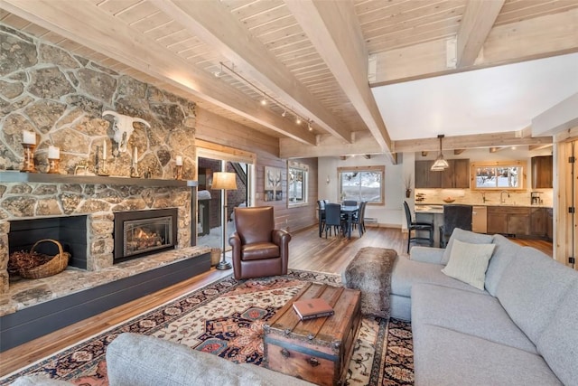 living room with a fireplace, wooden ceiling, wood-type flooring, and beam ceiling