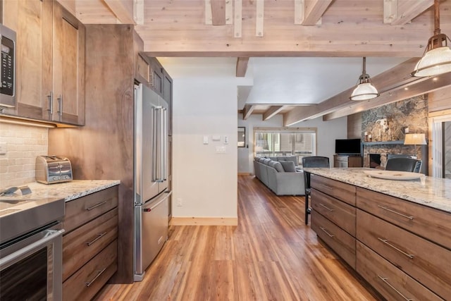 kitchen featuring hanging light fixtures, tasteful backsplash, beam ceiling, light stone counters, and stainless steel appliances