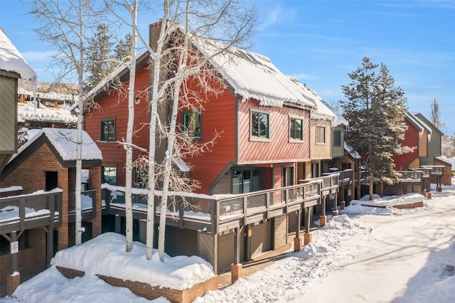 snow covered back of property with a garage