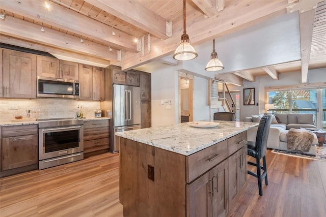 kitchen with a center island, stainless steel appliances, beamed ceiling, and decorative light fixtures