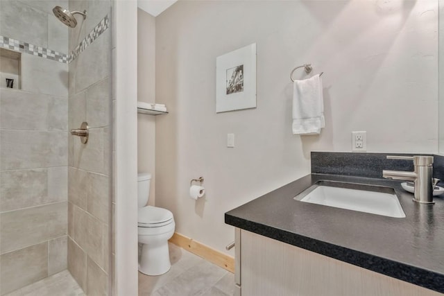 bathroom featuring vanity, toilet, and a tile shower