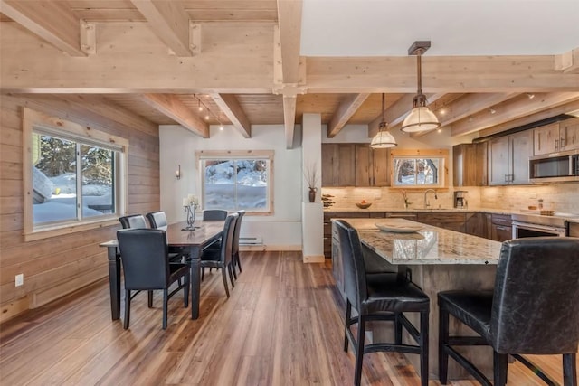 kitchen featuring beamed ceiling, wooden ceiling, hardwood / wood-style flooring, decorative light fixtures, and light stone counters