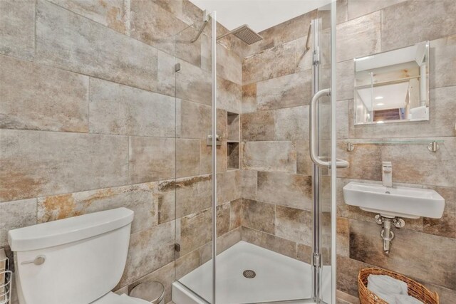 bathroom featuring sink, toilet, and a shower with shower door