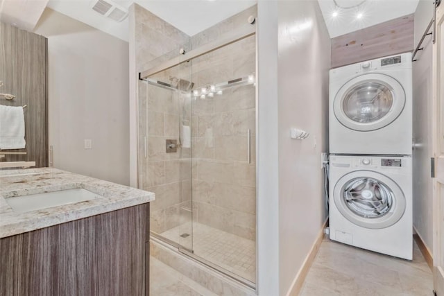 bathroom featuring vanity, stacked washer and dryer, and an enclosed shower