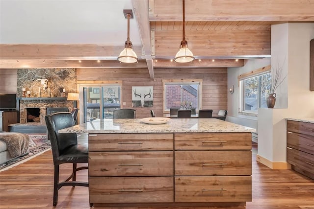 kitchen with light stone counters, pendant lighting, and beam ceiling