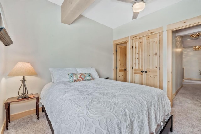 carpeted bedroom featuring beamed ceiling and ceiling fan