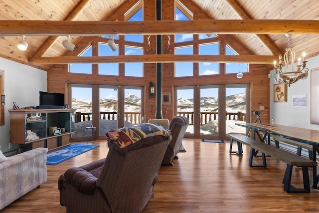 living area with lofted ceiling with beams, wood finished floors, a mountain view, an inviting chandelier, and wood ceiling