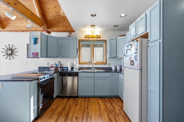 kitchen with black / electric stove, a peninsula, freestanding refrigerator, a sink, and stainless steel dishwasher