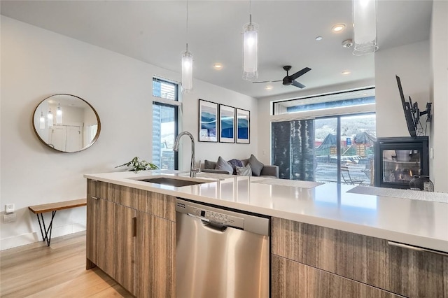 kitchen featuring stainless steel dishwasher, ceiling fan, sink, decorative light fixtures, and light hardwood / wood-style flooring