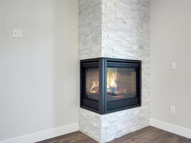 room details with hardwood / wood-style floors and a stone fireplace