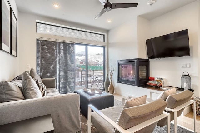 living room with hardwood / wood-style floors, ceiling fan, and a fireplace