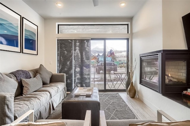 living room with a multi sided fireplace and hardwood / wood-style floors