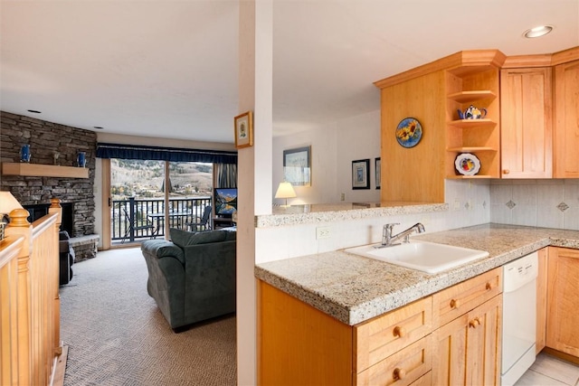 kitchen featuring dishwasher, sink, backsplash, light colored carpet, and a fireplace