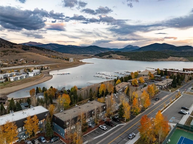 aerial view at dusk featuring a water and mountain view