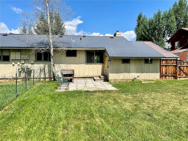 back of property with board and batten siding, metal roof, a yard, and fence