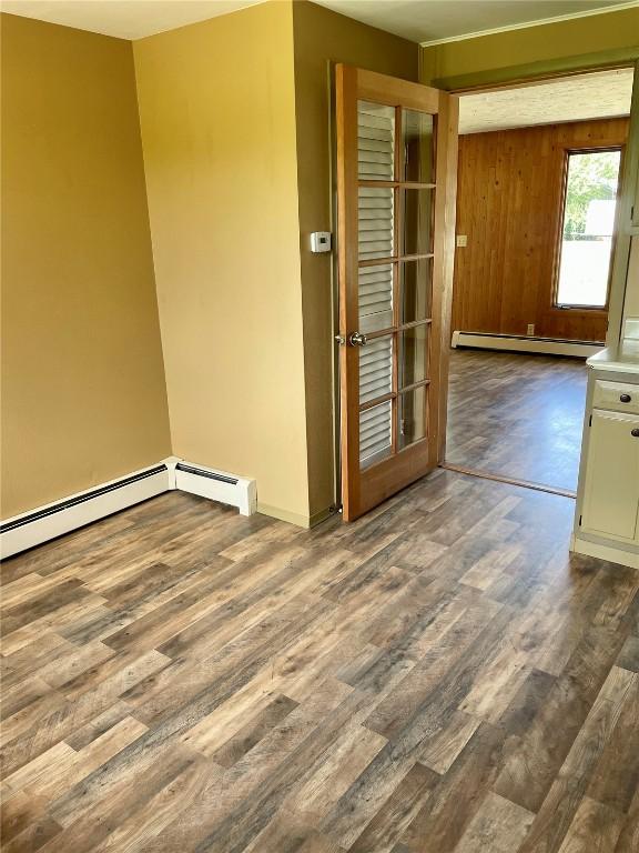 empty room featuring a baseboard heating unit and dark wood-type flooring