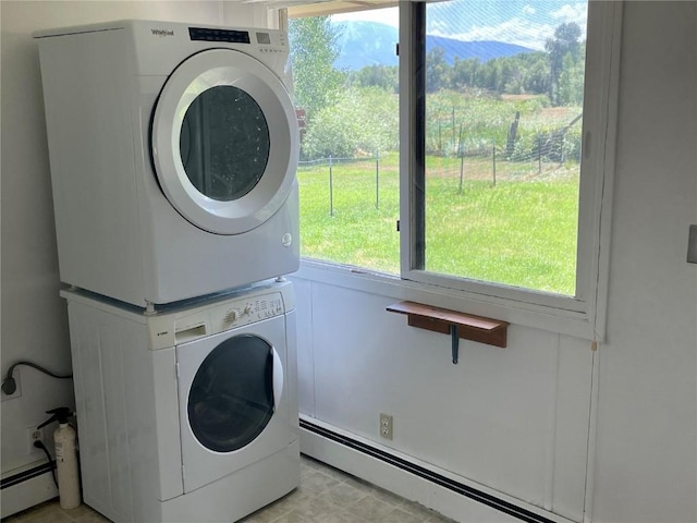 clothes washing area featuring laundry area, a baseboard radiator, and stacked washing maching and dryer