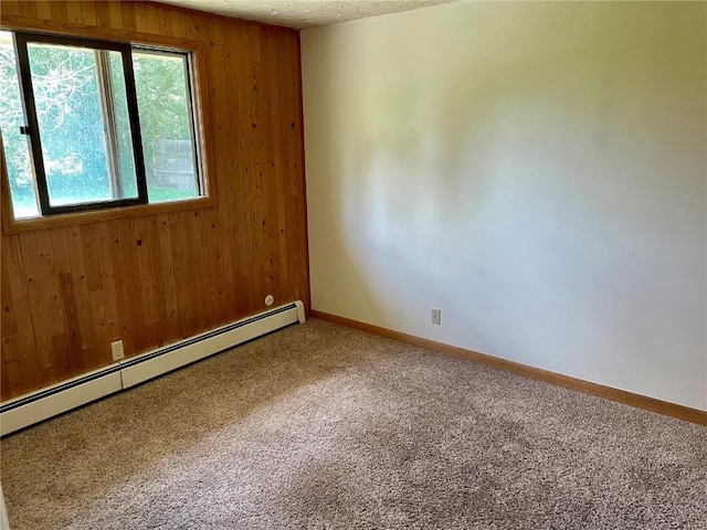 empty room featuring baseboards, a baseboard radiator, a textured ceiling, carpet floors, and wood walls