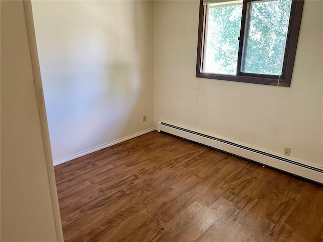 unfurnished room with a baseboard radiator, baseboards, and wood finished floors