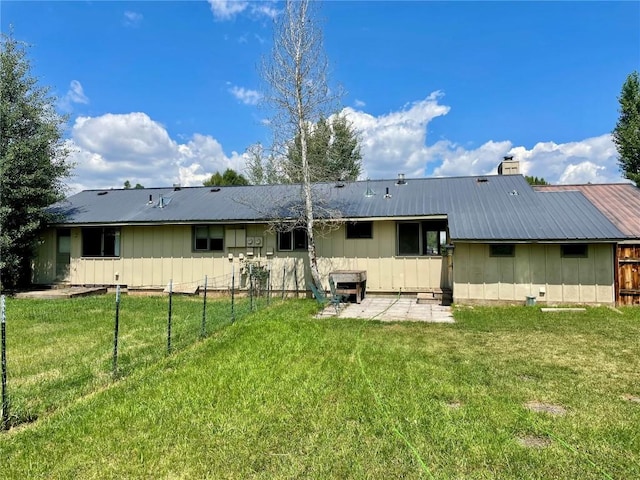 back of house with metal roof, a yard, and a chimney