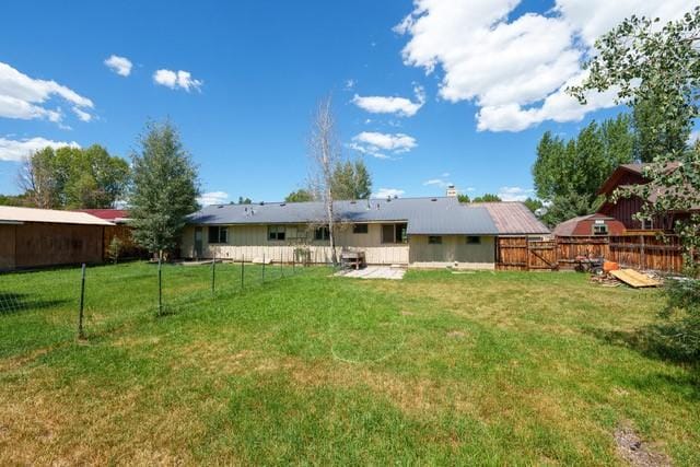 rear view of property featuring a fenced backyard and a yard