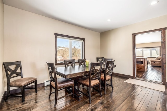 dining area featuring plenty of natural light, baseboard heating, and dark wood-type flooring