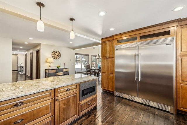 kitchen with built in appliances, light stone countertops, dark wood-type flooring, and hanging light fixtures