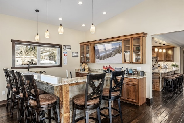 bar featuring light stone countertops, decorative backsplash, dark hardwood / wood-style flooring, and decorative light fixtures