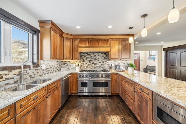 kitchen featuring light stone countertops, sink, dark hardwood / wood-style floors, decorative light fixtures, and appliances with stainless steel finishes