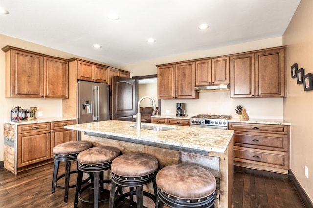 kitchen featuring sink, dark wood-type flooring, a breakfast bar area, high quality appliances, and a center island with sink