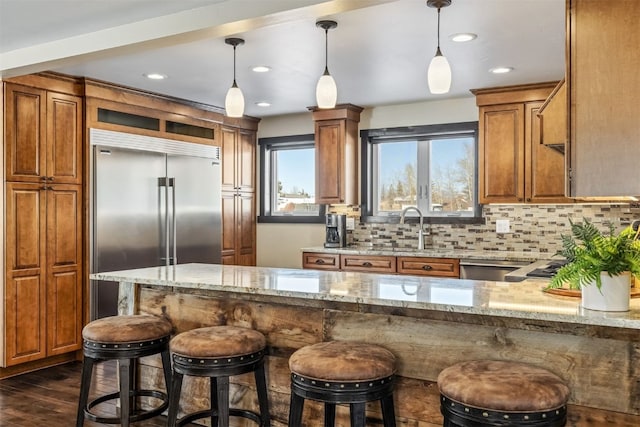 kitchen with decorative backsplash, appliances with stainless steel finishes, decorative light fixtures, and light stone counters