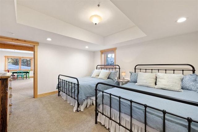 carpeted bedroom featuring a raised ceiling and multiple windows