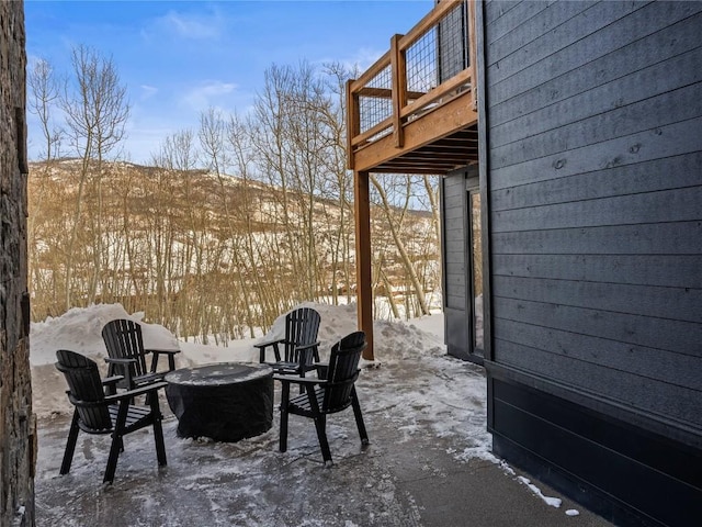 snow covered patio featuring a fire pit and a wooden deck