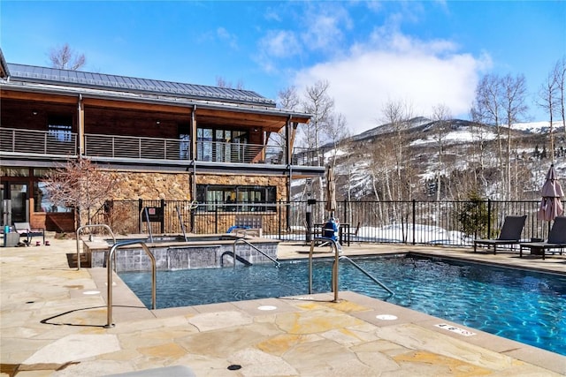 pool with a mountain view, a hot tub, a patio, and fence