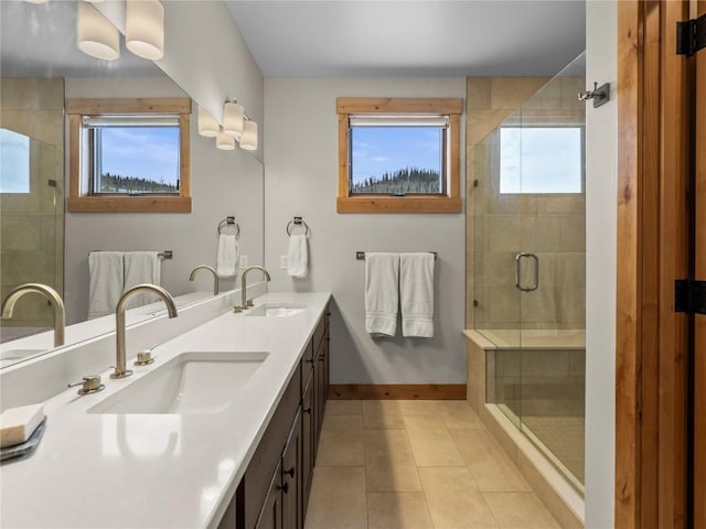 bathroom featuring a sink, baseboards, a shower stall, and tile patterned flooring