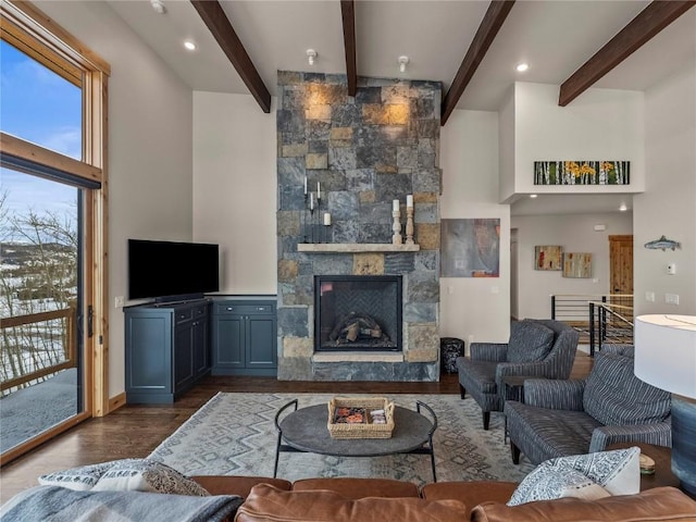 living area featuring beamed ceiling, a fireplace, a towering ceiling, and wood finished floors