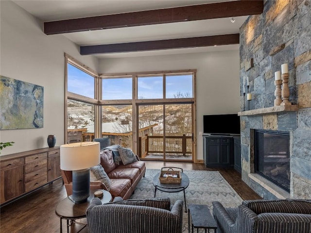 living room featuring dark wood finished floors, beamed ceiling, a fireplace, and a towering ceiling