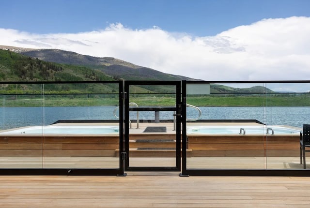 dock area featuring a water and mountain view and a hot tub