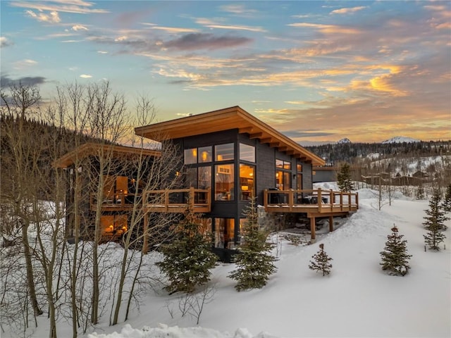 snow covered house featuring a deck