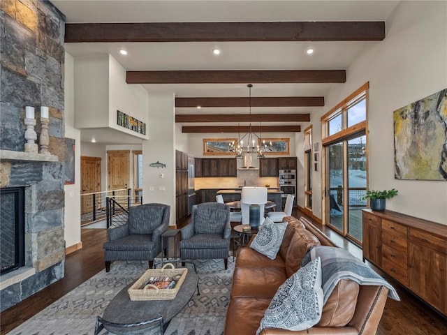 living area featuring dark wood finished floors, an inviting chandelier, beamed ceiling, and a fireplace