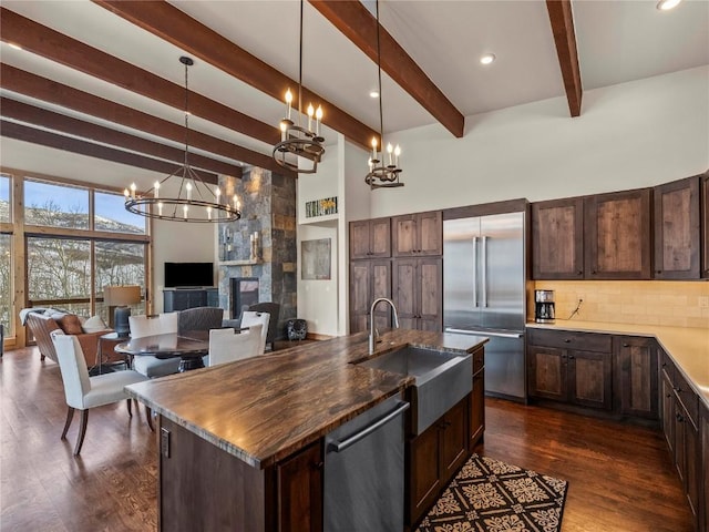 kitchen with a sink, tasteful backsplash, dark brown cabinetry, appliances with stainless steel finishes, and a chandelier